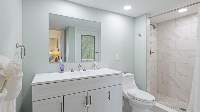 bathroom featuring a tile shower, vanity, and toilet