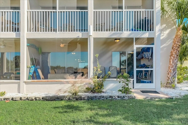 view of exterior entry with a balcony and a yard