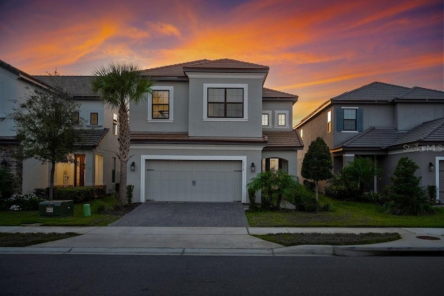 view of front of property featuring a garage, decorative driveway, and stucco siding