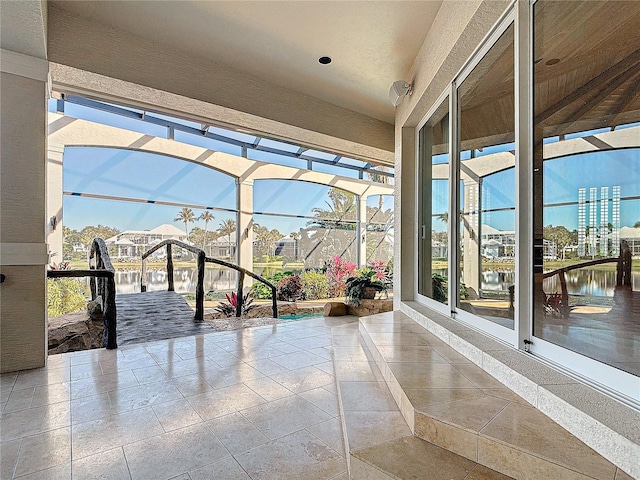 unfurnished sunroom featuring a wealth of natural light, a water view, and a pool