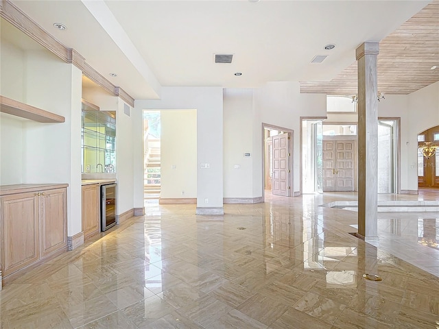 unfurnished living room with decorative columns, french doors, and beverage cooler