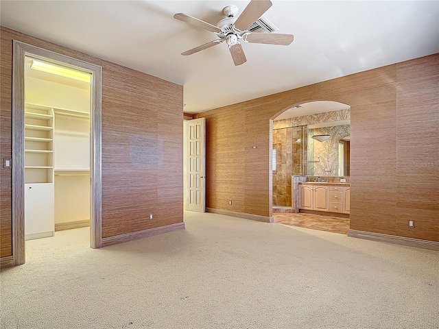 unfurnished bedroom featuring ceiling fan, light colored carpet, a walk in closet, and a closet