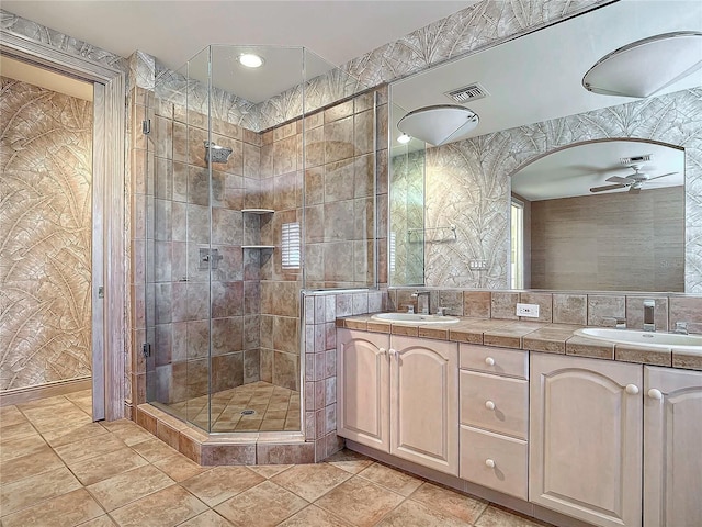 bathroom with ceiling fan, vanity, tile walls, and walk in shower