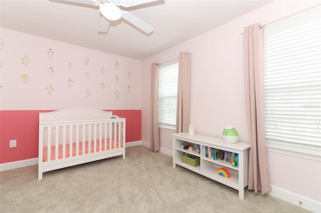 carpeted bedroom with ceiling fan and a nursery area