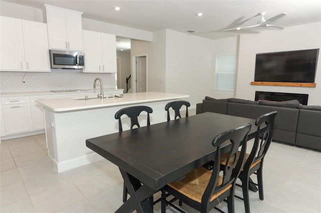 tiled dining room featuring ceiling fan and sink