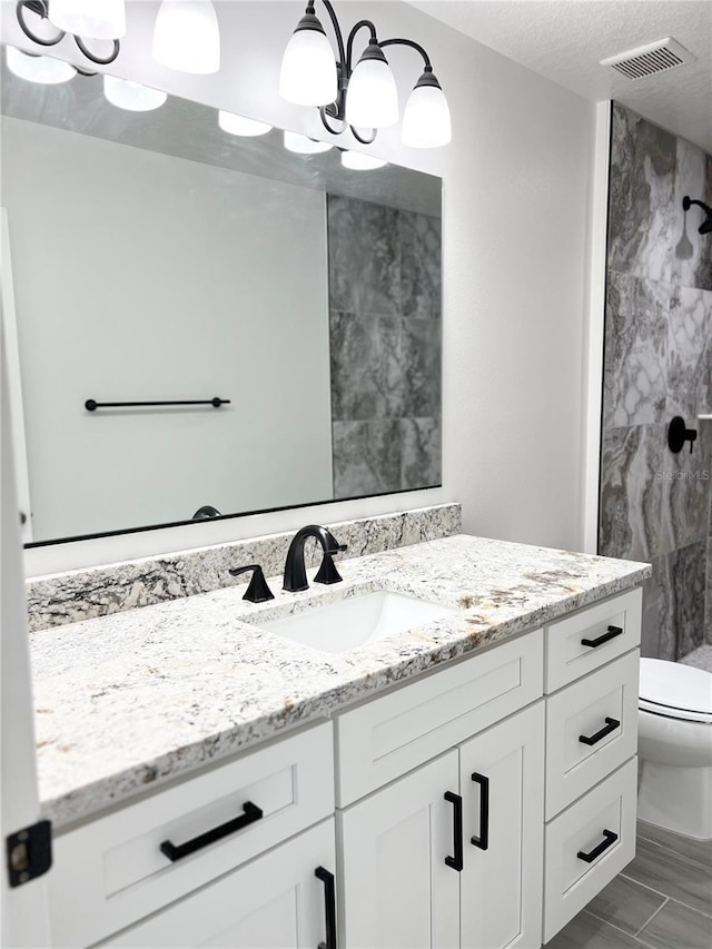 bathroom with toilet, vanity, a chandelier, and walk in shower