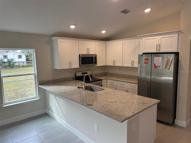 kitchen featuring appliances with stainless steel finishes, white cabinets, kitchen peninsula, and light stone countertops