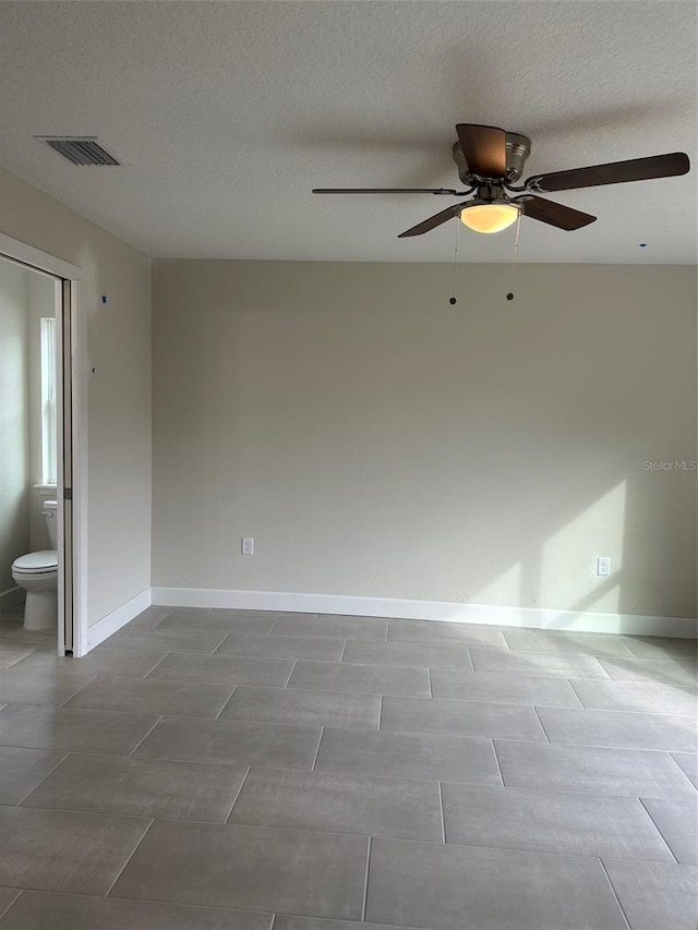 empty room with ceiling fan and a textured ceiling