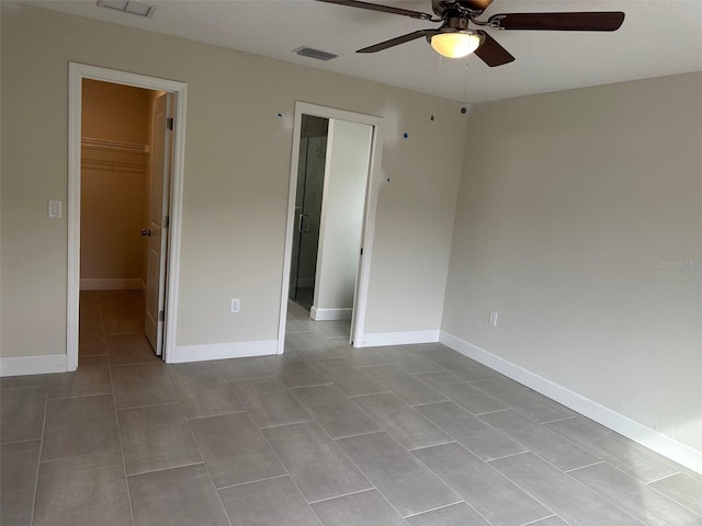 unfurnished bedroom with light tile patterned flooring, ceiling fan, a walk in closet, and a closet