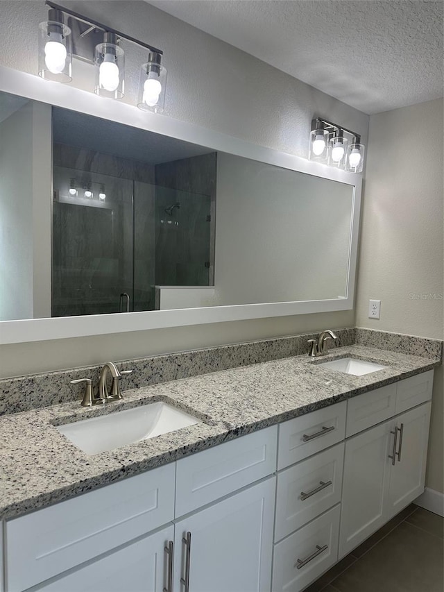 bathroom featuring tile patterned floors, a textured ceiling, an enclosed shower, and vanity