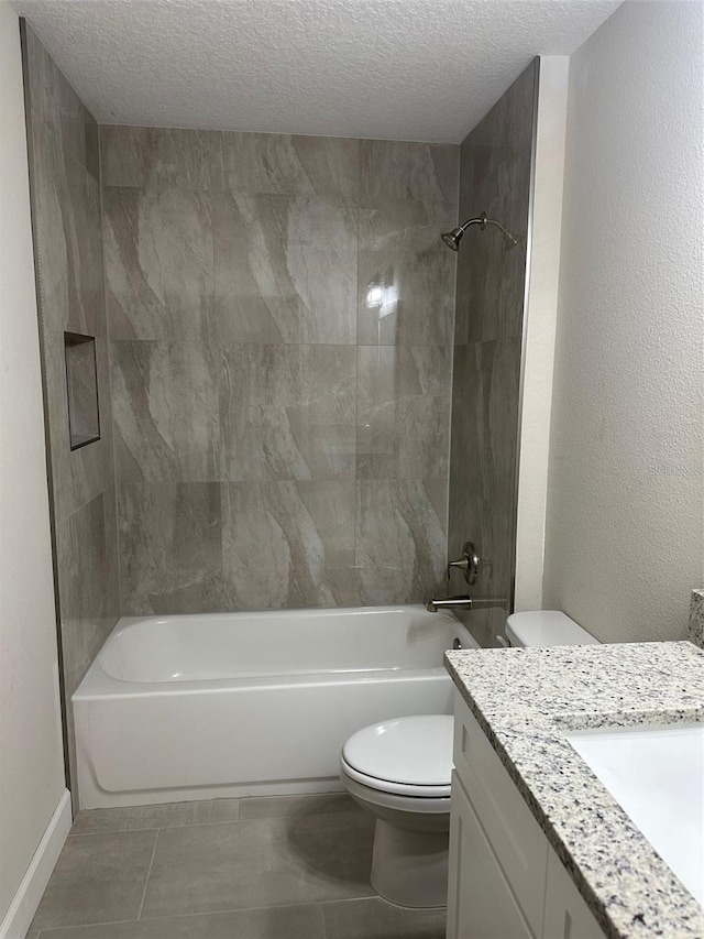 full bathroom with a textured ceiling, tiled shower / bath, tile patterned floors, vanity, and toilet