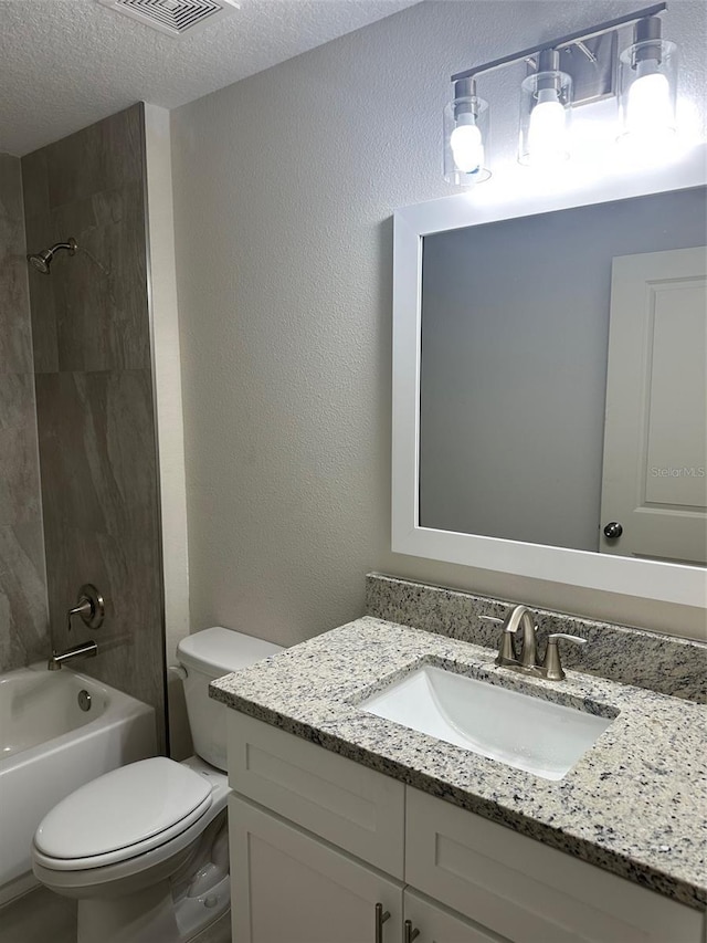 full bathroom with a textured ceiling, toilet, vanity, and tiled shower / bath