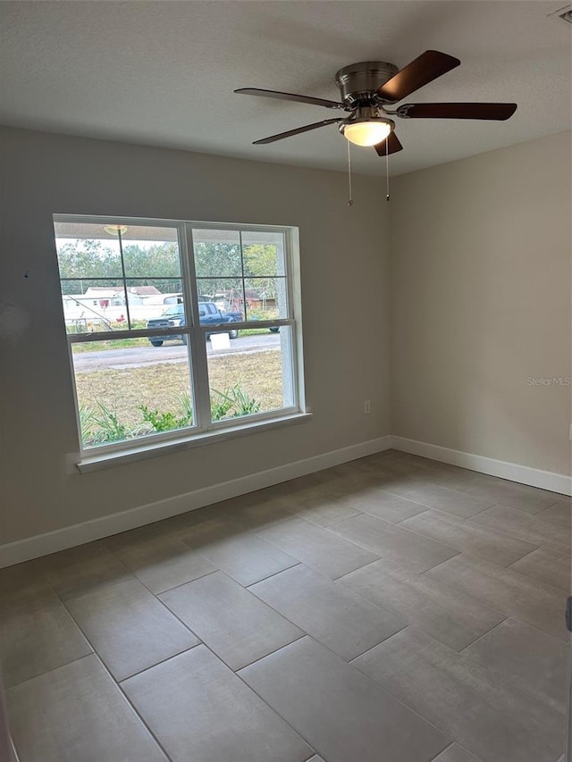 empty room with ceiling fan and light tile patterned flooring