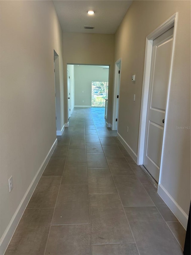 hall featuring dark tile patterned flooring