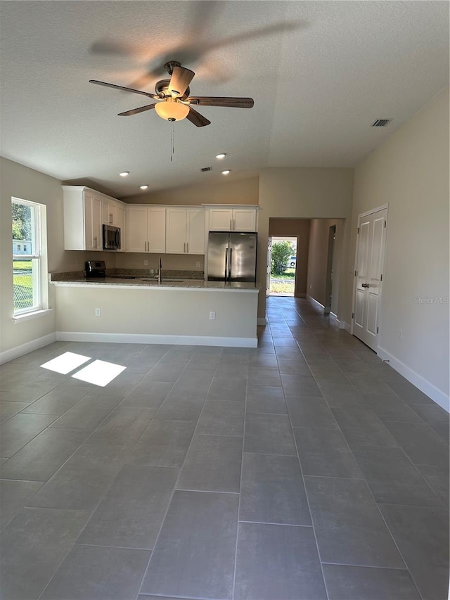 kitchen featuring white cabinetry, kitchen peninsula, appliances with stainless steel finishes, and dark tile patterned flooring