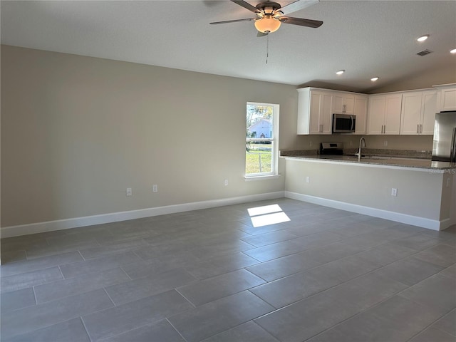 kitchen featuring kitchen peninsula, lofted ceiling, sink, appliances with stainless steel finishes, and white cabinets