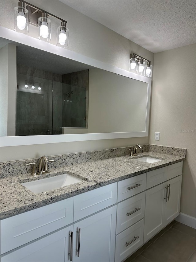 bathroom featuring a textured ceiling, vanity, tile patterned flooring, and an enclosed shower