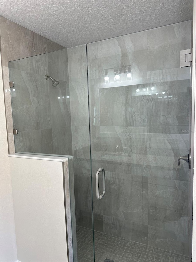 bathroom featuring a textured ceiling and a shower with shower door