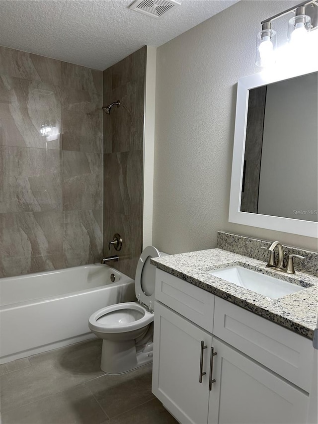 full bathroom with a textured ceiling, toilet, vanity, and tiled shower / bath