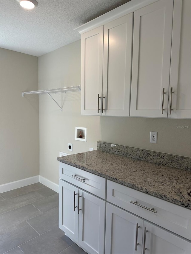 washroom with cabinets, hookup for an electric dryer, a textured ceiling, and hookup for a washing machine