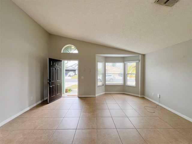 tiled entrance foyer with lofted ceiling and a textured ceiling