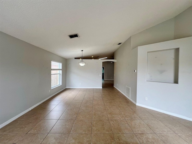 spare room with vaulted ceiling, a textured ceiling, and light tile patterned floors