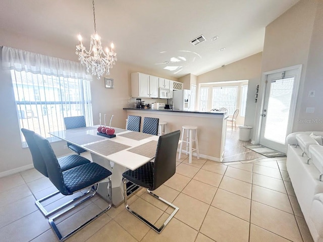 dining area with light tile patterned floors, an inviting chandelier, and lofted ceiling