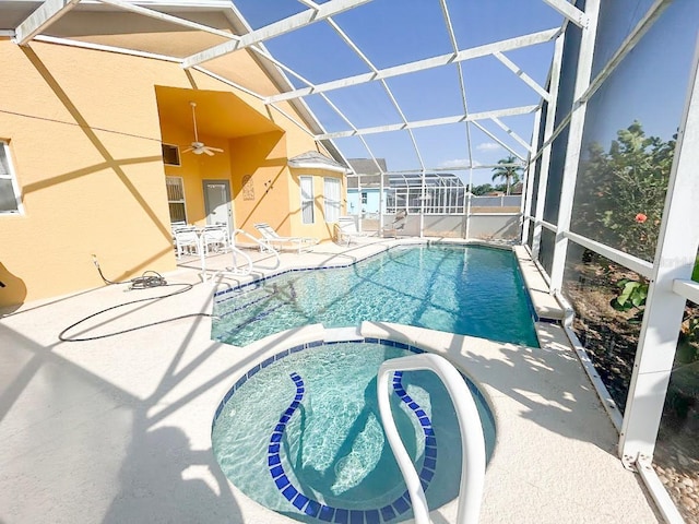 view of swimming pool with a patio area, ceiling fan, glass enclosure, and an in ground hot tub