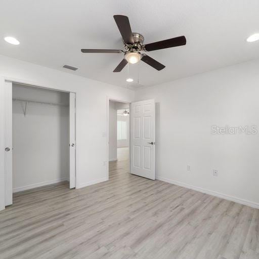 unfurnished bedroom featuring ceiling fan, a closet, and light hardwood / wood-style floors