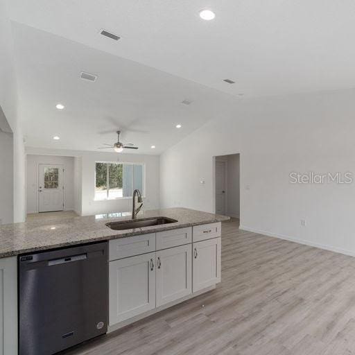 kitchen with dishwasher, sink, ceiling fan, light stone countertops, and white cabinetry