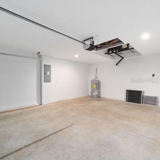 garage with electric panel, a garage door opener, and water heater