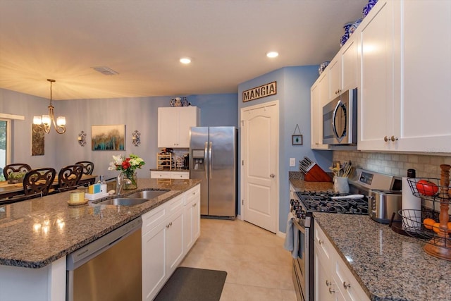 kitchen featuring an inviting chandelier, a center island with sink, sink, appliances with stainless steel finishes, and white cabinetry