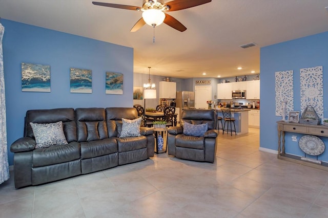 living room with ceiling fan with notable chandelier and light tile patterned floors