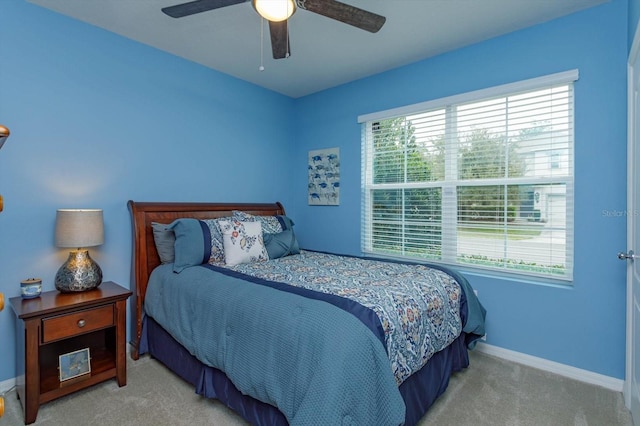 bedroom with ceiling fan, light colored carpet, and multiple windows