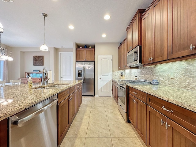 kitchen featuring light stone countertops, appliances with stainless steel finishes, backsplash, sink, and pendant lighting