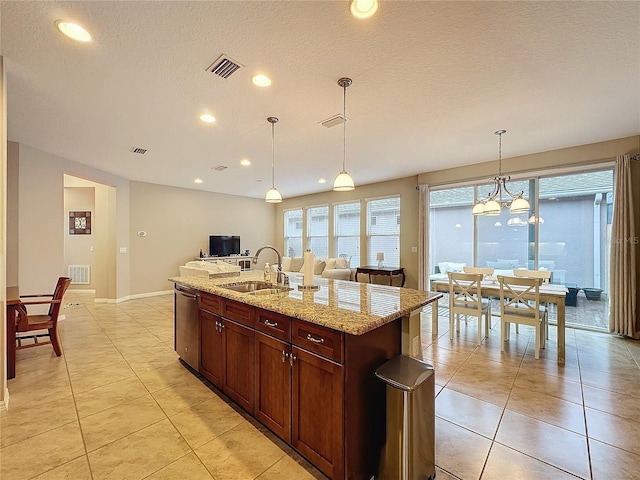 kitchen featuring a kitchen island with sink, hanging light fixtures, sink, stainless steel dishwasher, and light stone counters