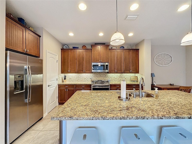 kitchen with a kitchen breakfast bar, hanging light fixtures, light tile patterned flooring, and stainless steel appliances