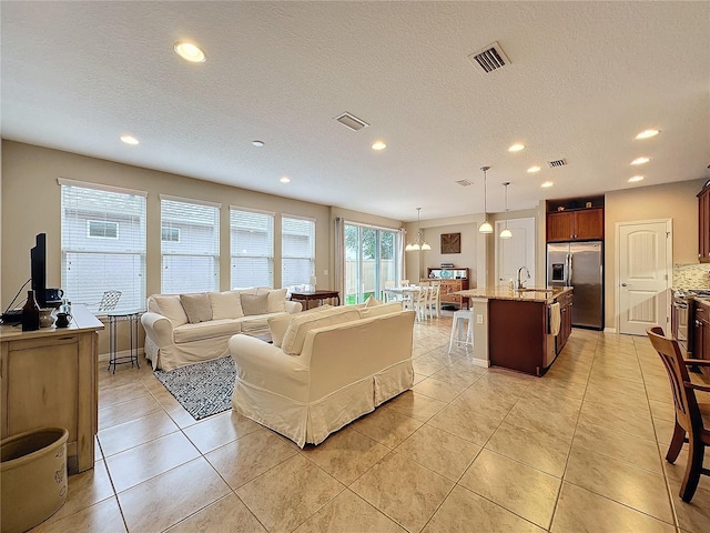 living room featuring a notable chandelier, light tile patterned flooring, sink, and a textured ceiling