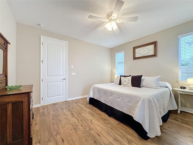 bedroom with ceiling fan, light hardwood / wood-style floors, and a textured ceiling