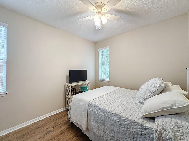 bedroom with ceiling fan, dark hardwood / wood-style flooring, and a textured ceiling