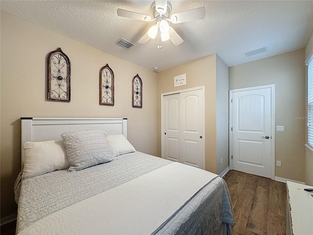 bedroom featuring a textured ceiling, ceiling fan, dark wood-type flooring, and a closet