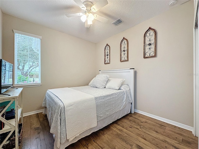 bedroom with hardwood / wood-style floors, a textured ceiling, and ceiling fan