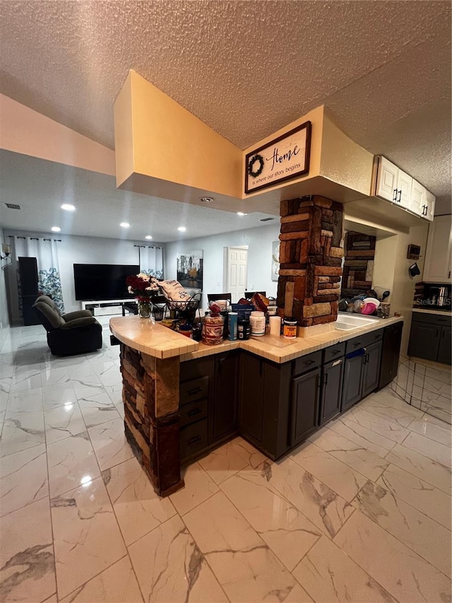 kitchen featuring a textured ceiling, dark brown cabinets, and vaulted ceiling