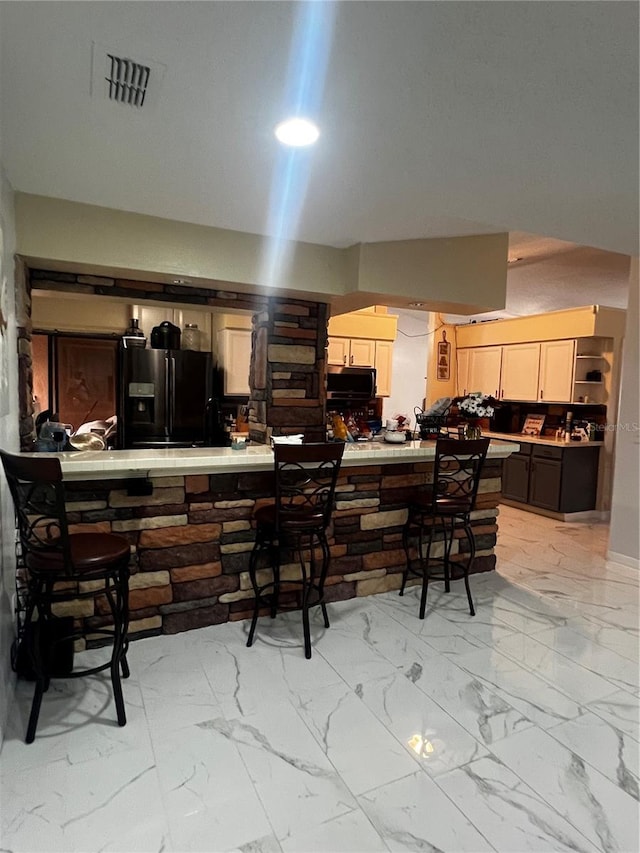 kitchen featuring refrigerator with ice dispenser, a breakfast bar, and kitchen peninsula