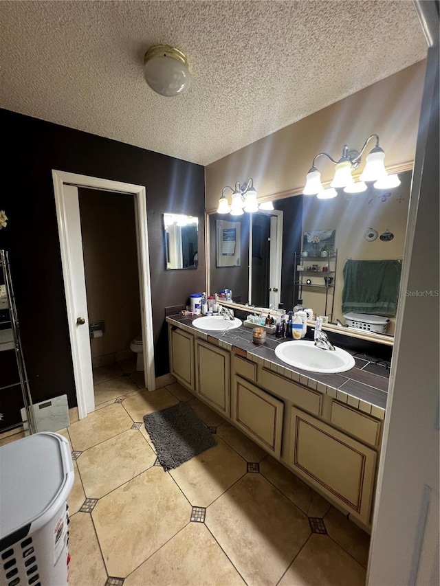 bathroom featuring tile patterned flooring, vanity, toilet, and a textured ceiling