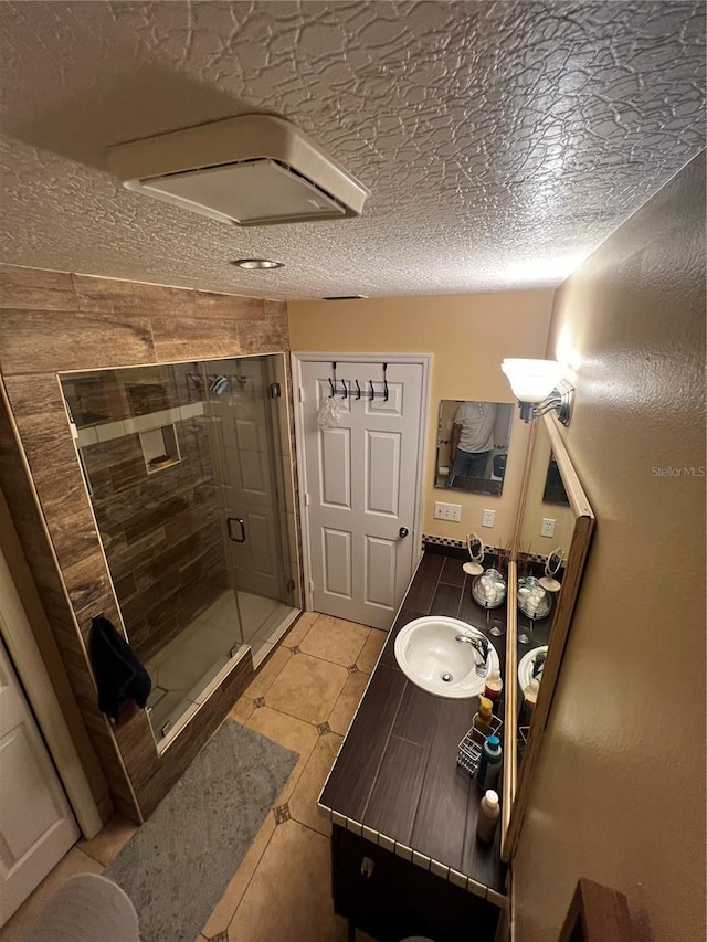 bathroom with an enclosed shower, a textured ceiling, vanity, wooden walls, and tile patterned flooring