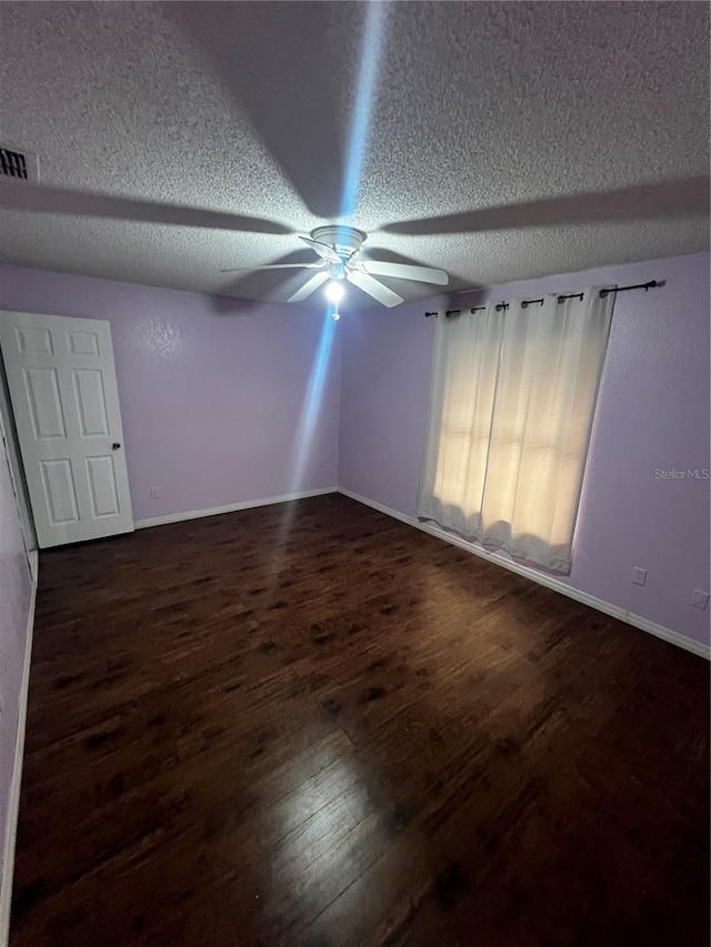 unfurnished room with a textured ceiling, ceiling fan, and dark wood-type flooring