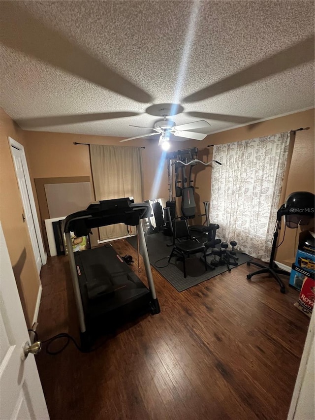 exercise area featuring a textured ceiling, dark hardwood / wood-style flooring, and ceiling fan