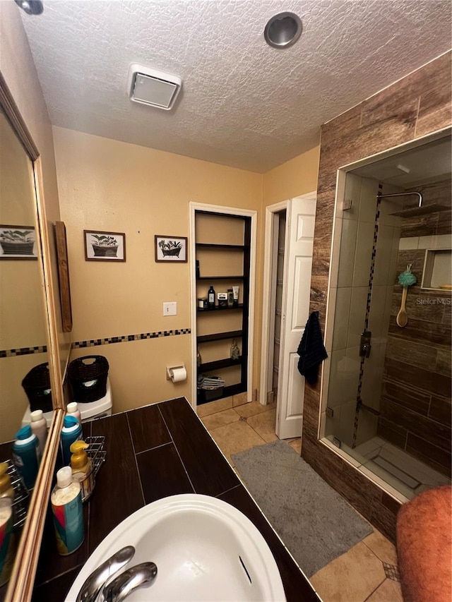 bathroom featuring tile patterned flooring, a tile shower, and sink