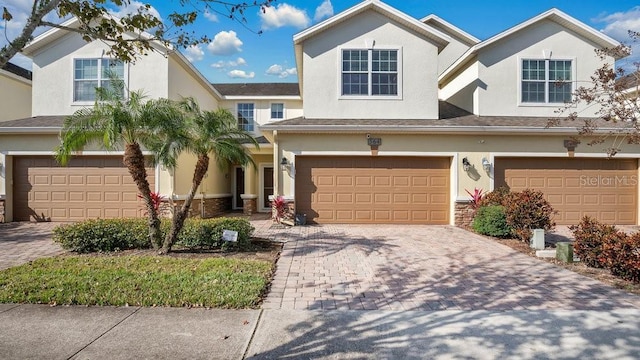 view of front of house with a garage, decorative driveway, and stucco siding